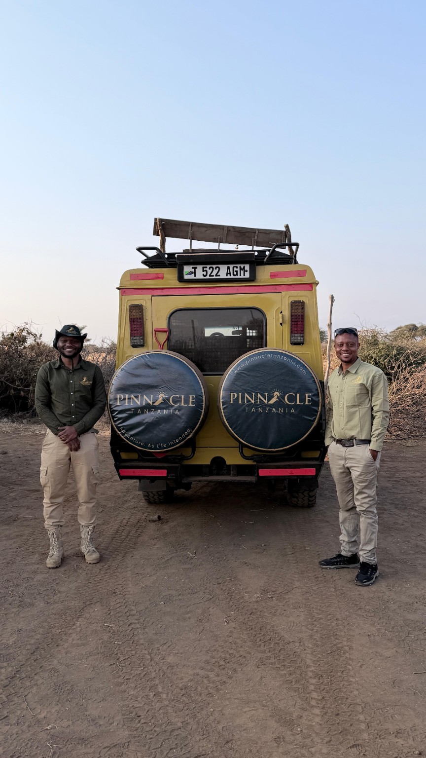 Pinnacle safari guides beside a branded safari vehicle in Tanzania
